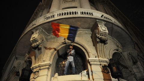 A protester waves the Romanian flag from a window of Bucharest University headquarters in Bucharest earlier this year