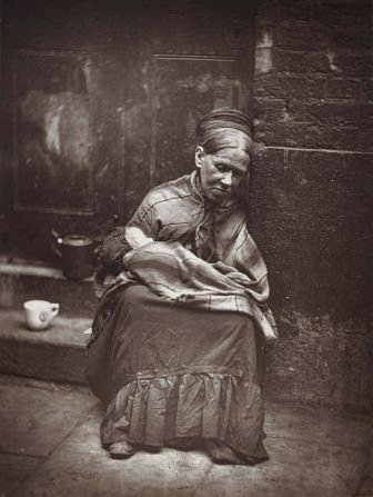 Dickens' work often focused on extreme poverty; here, a photo from an 1877 book on London street life shows a destitute mother sitting with her infant on stone steps.