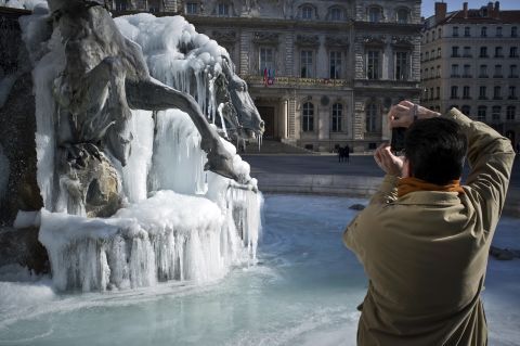 A man takes pictures of a Bartholdi fountain covered by ice on February 6, 2012 on Terraux square in Lyon, eastern France. In France, 39 of the country's 101 regions were on alert for deep cold or snow, down from more than half the regions at the weekend.