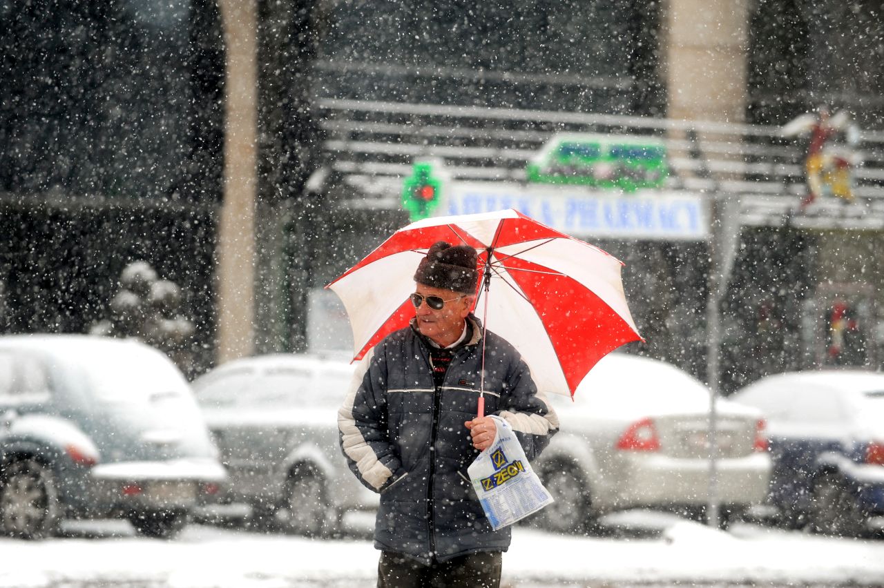 A man walks under an umbrella during a snowfall in downtown Skopje on February 6, 2012.