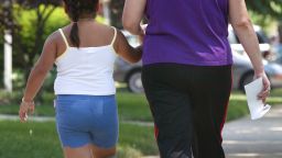 A young girl walks with her mother along a sidewalk July 2, 2003 in Des Plaines, Illinois. According to Food and Drug Administration Commissioner Dr. Mark McClellan, 13 percent of children ages 6 to 11 are obese, double the number 20 years ago. 