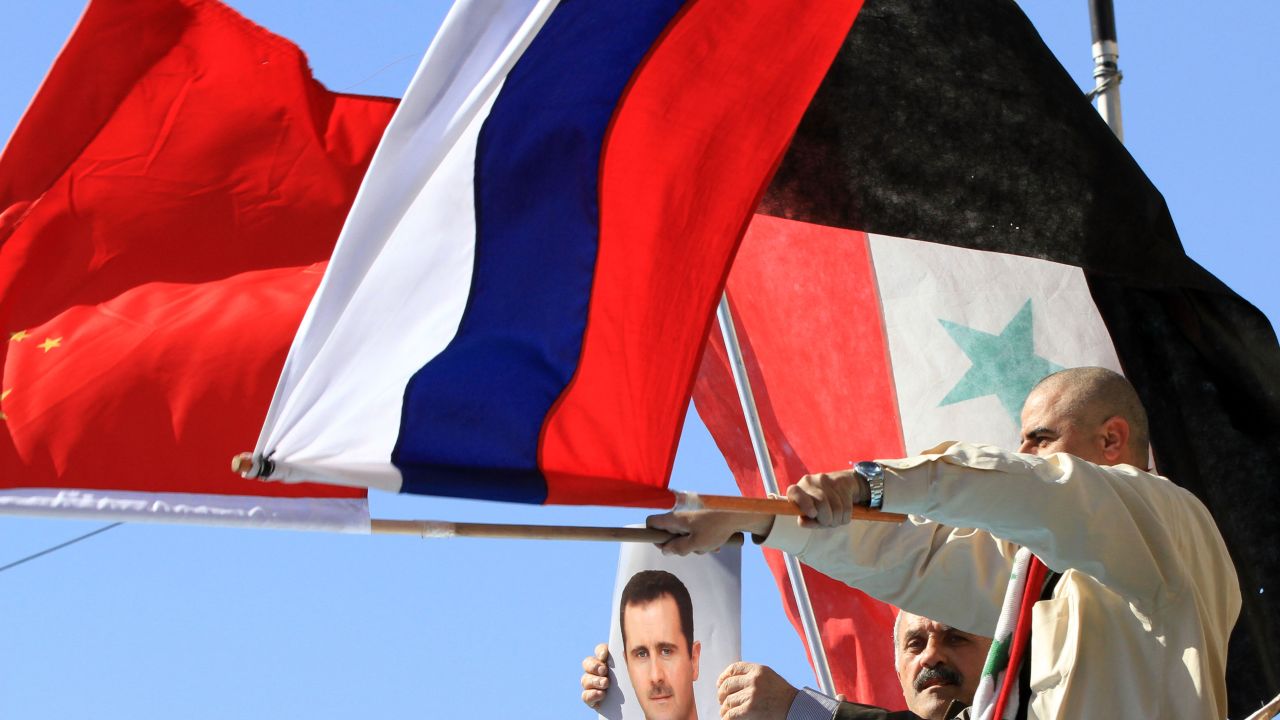 Supporters of Syria's president wave Russian, Chinese and Syrian flags during a pro-regime rally in central Damascus.
