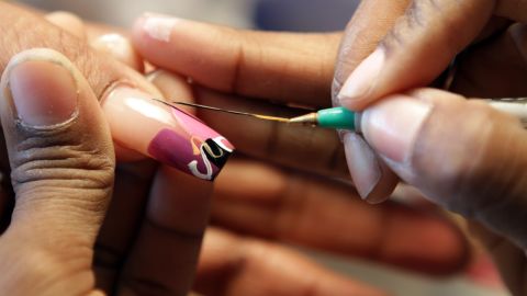 Tashina "Poochie" Green uses a stripe brush to add subtle detail to a customer's nails.