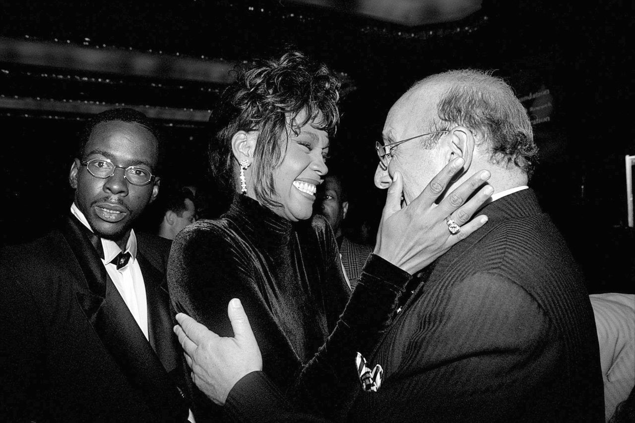 Bobby Brown, left, looks on as his wife, Whitney Houston, congratulates Clive Davis, president of Arista Records, at a 1995 benefit dinner for Davis. 