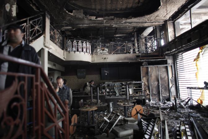 People stand in a damaged building after it burned in central Athens on February 13. Greek lawmakers approved radical budget cuts to secure a 130 billion euro rescue package aimed at averting bankruptcy, after a day of street battles left dozens injured and Athens buildings ablaze.