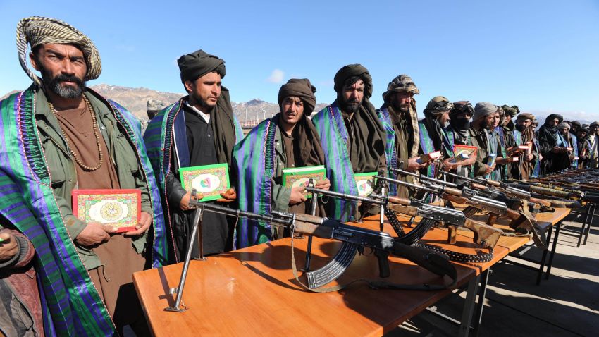 In a file picture taken on January 30, 2012, Taliban fighters stand with their weapons as they hold the Muslim holy book Koran after they joined Afghan government forces during a ceremony in Herat province. The medieval Taliban who ran Afghanistan with the Koran in one hand and a gun in the other now tweet and talk peace, but they remain a potent threat as a NATO withdrawal looms.