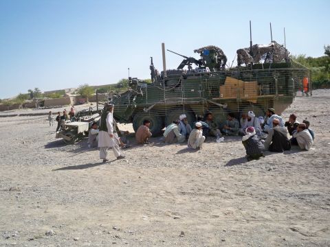 U.S. soldiers shelter in the shade of a Stryker fighting vehicle as they discuss poppy eradication with elders from Barbary Soznay, Afghanistan.