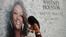 A Fillipino fan of US pop diva, Whitney Houston, signs a tribute mural displaying a portrait of her idol at a mall in Manila on February 17, 2012. Houston, who died on February 11 aged 48 in a Beverly Hills hotel, will be laid to rest on February 18, after a private funeral service at the New Jersey Baptist church where she grew up singing in a gospel choir. AFP PHOTO / TED ALJIBE (Photo credit should read TED ALJIBE/AFP/Getty Images) 