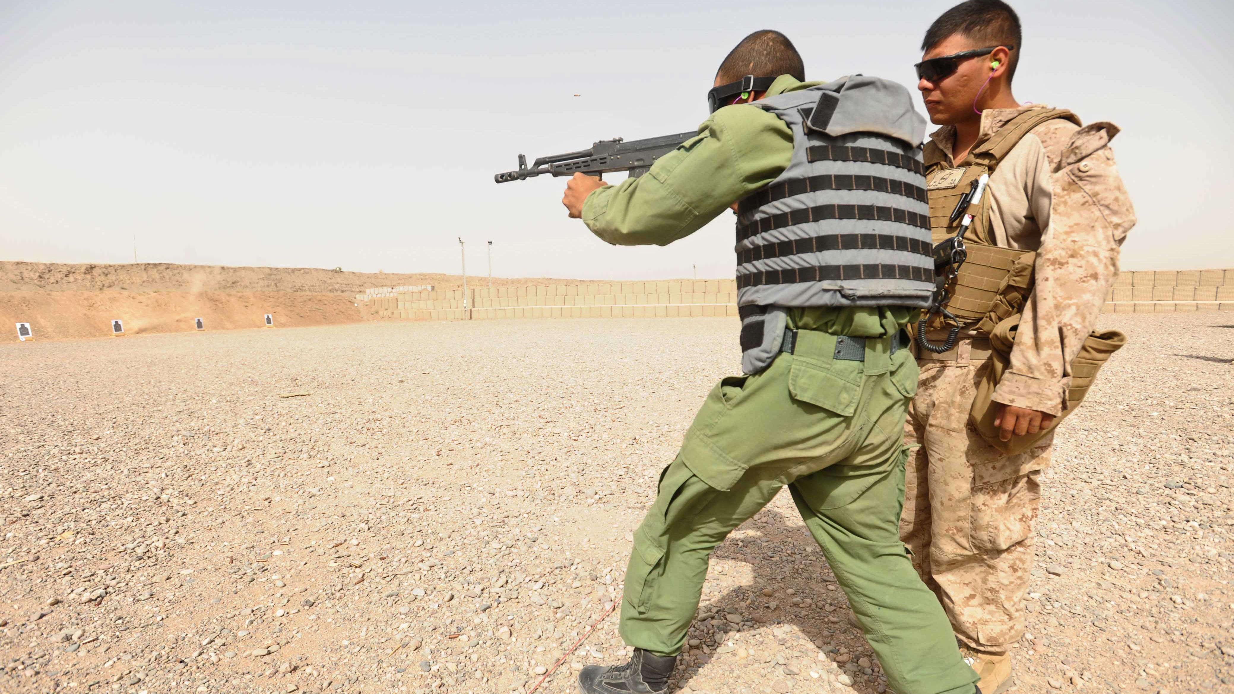 An Afghan police trainee practices shooting as a U.S. Marine looks on at Adraskan Police Training Center on July 15, 2011.