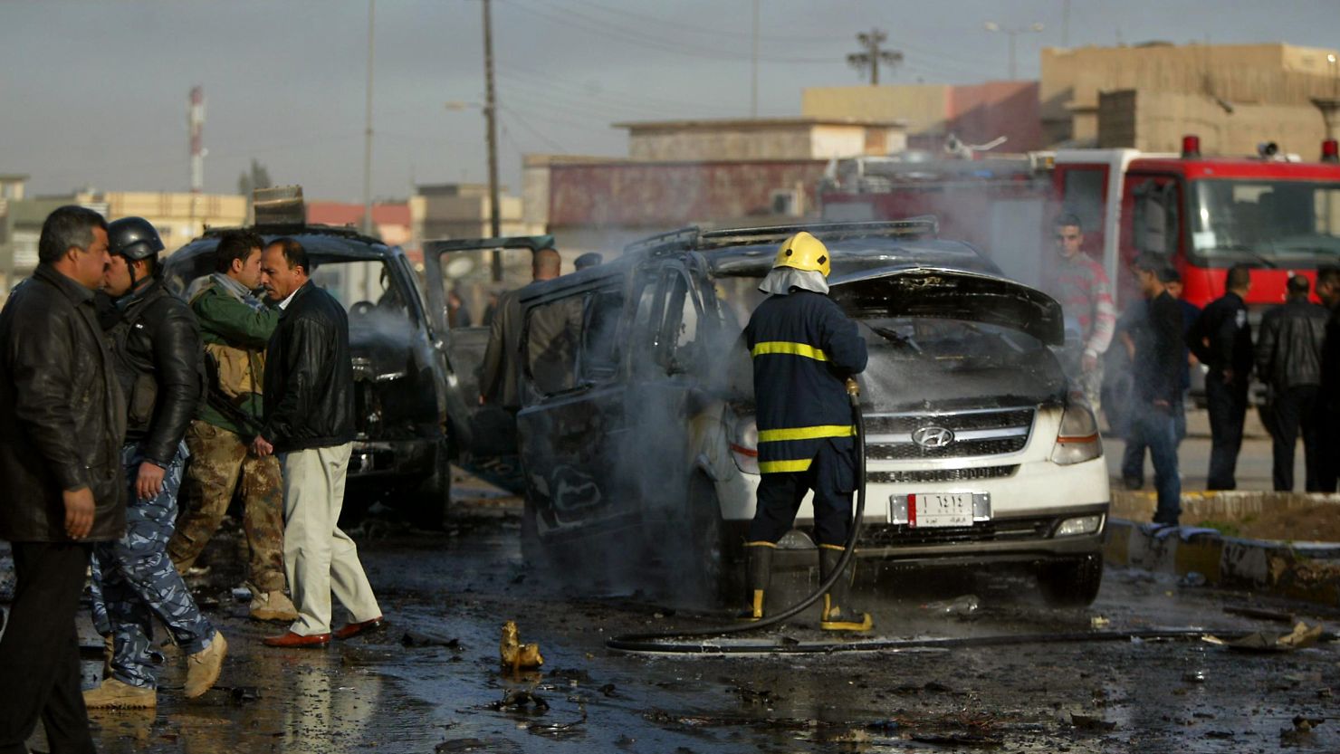 An Iraqi firefighter douses a car as security forces inspect the site of a blast in the northern city of Kirkuk on February 23, 2012. 