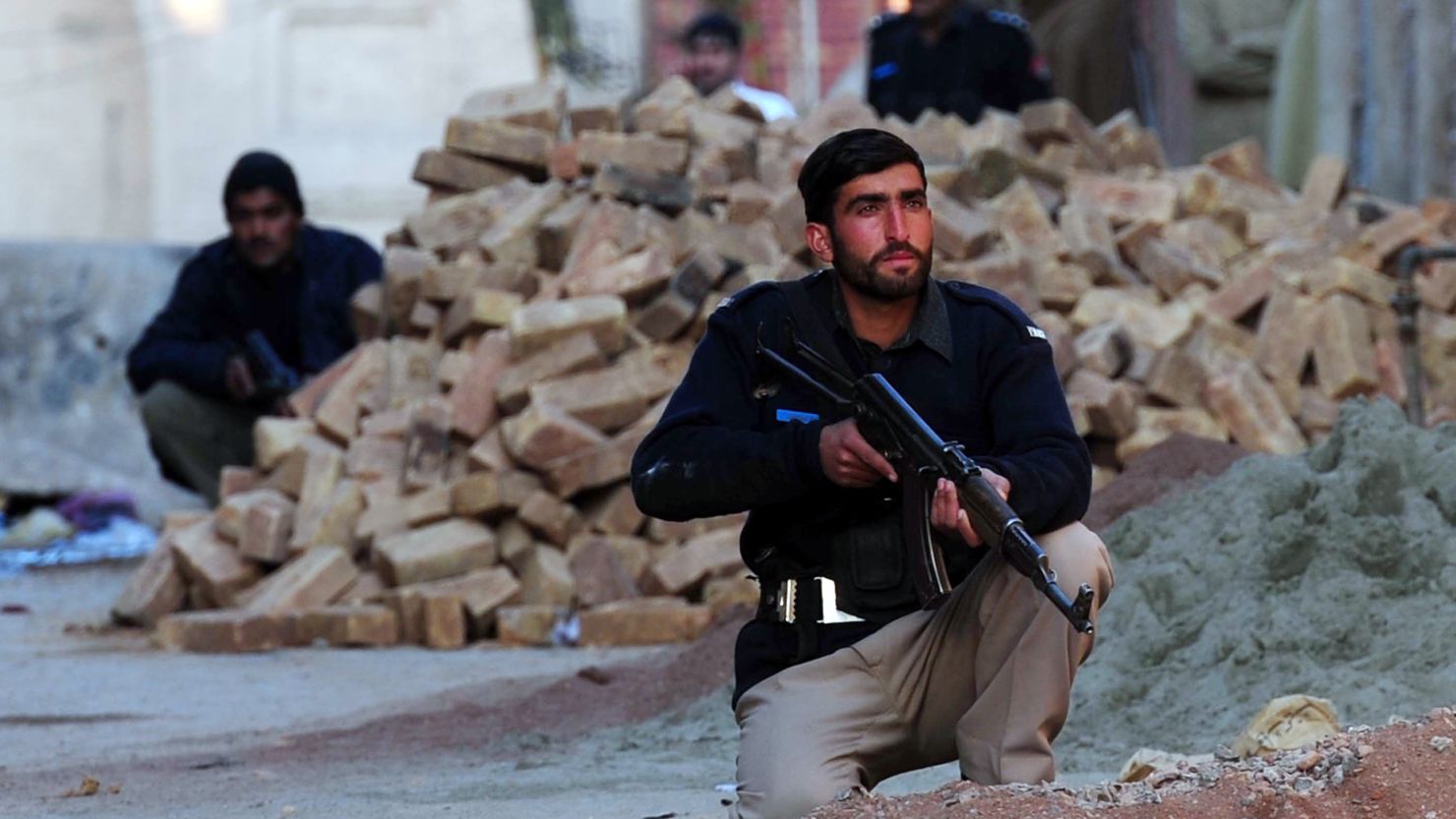 Pakistani policemen take position during a militant attack on a police station in Peshawar on February 24, 2012.