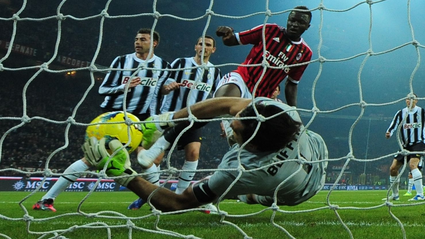 Juventus goalkeeper Gianluigi Buffon claws back a goalbound header from  AC Milan midfielder Sulley Ali Muntari.