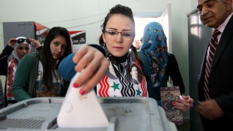 A Syrian woman wearing a scarf with pictures of Syrian President Bashar al-Assad casts her vote on a new constitution at a polling station in Damascus on February 26.