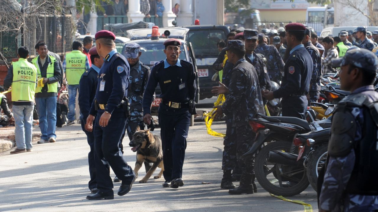 Nepalese policemen walk with a sniffer dog at the site of a bomb blast on February 27, 2012. 