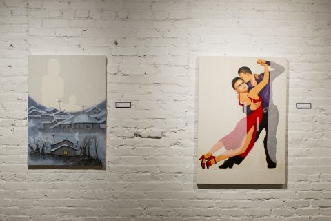 In "Hillside Slums," the painting on the left, an image of Song's mother dominates the skyline over the house he grew up in. She told Song she was worried about Kim Jong Il's health before she herself died in the famine of the 1990s. By putting Kim in drag in "Fall Into My Arms," Song glamorizes all things foreign and wonders whether life would not be more exciting for North Korea if it was opened to the outside. 