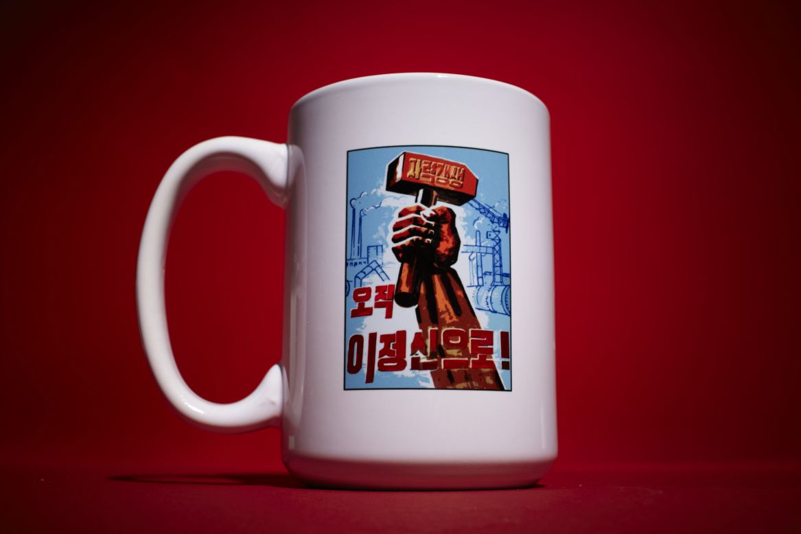 Now available to foreigners on a coffee mug, Song Byeok painted this same design on three factory billboards inside North Korea. It says "Self-Reliance: This Is Our Only Belief." The mug is made in China. 