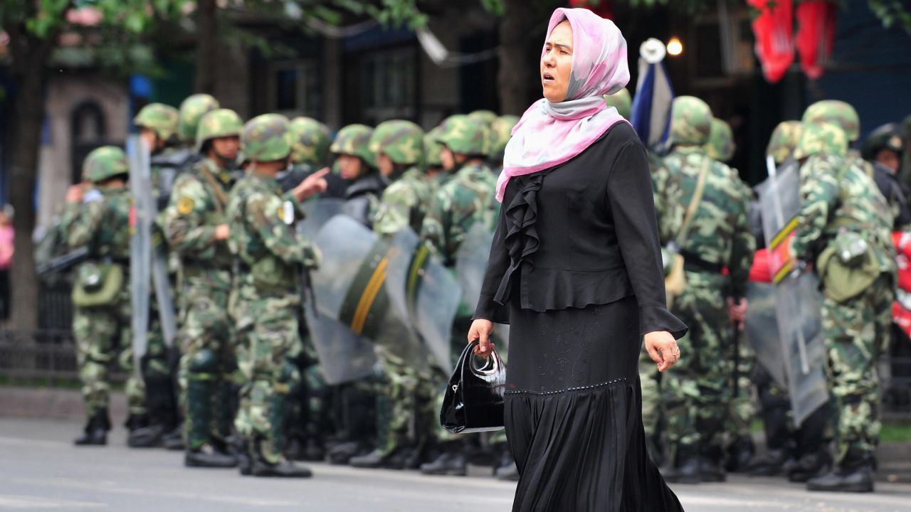 A Uighur woman crosses a street in front of Chinese soldiers in Urumqi in this file picture dated July 15, 2009