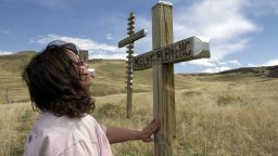A woman known only as Golden Eagle pray's next to one of the thirteen original crosses April 20, 2004 that was built and placed in Clements Park next to Columbine High School after the shooting on April 20, 1999.