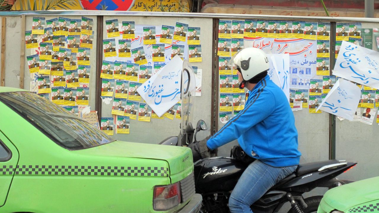 An Iranian motorcyclist looks at parliamentary election posters Wednesday in Tehran.