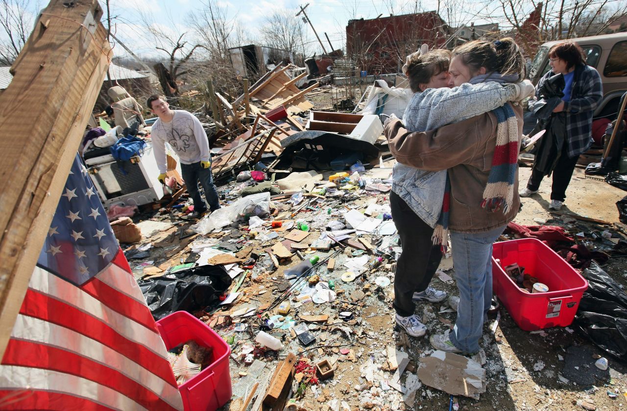 Melody Zollman, left, gets a hug from her sister Michelle Browning as they stand among the remains of Zollman's home in Henryville after it was destroyed by a tornado on Friday.