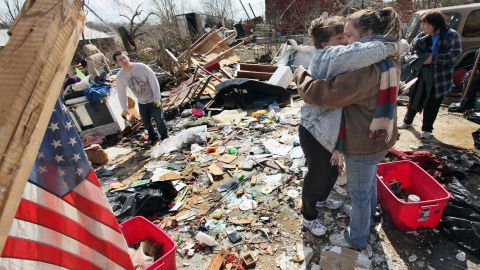 Melody Zollman, left, gets a hug from her sister Michelle Browning as they stand among the remains of Zollman's home in Henryville after it was destroyed by a tornado on Friday.