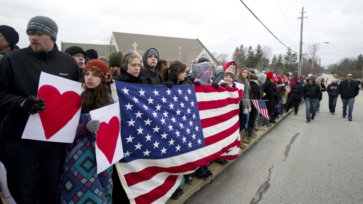 People stand along the road in Chardon, Ohio, before the funeral for 16-year-old Danny Parmertor.