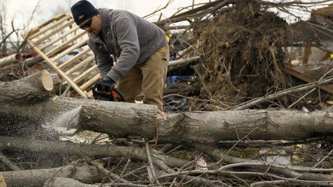 Troy Lewis cuts up a tree on Sunday that fell when a tornado passed through Marysville, Indiana.