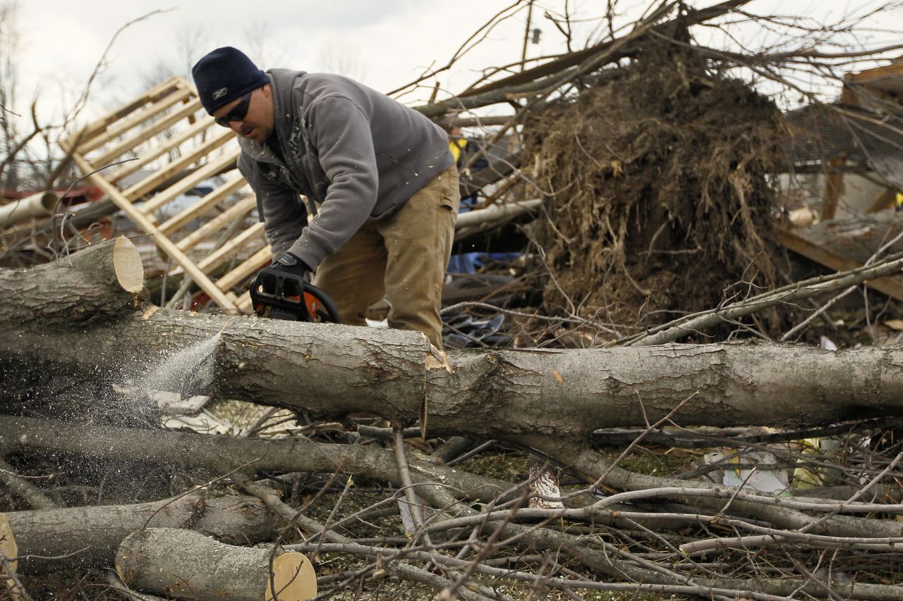 Troy Lewis cuts up a tree on Sunday that fell when a tornado passed through Marysville, Indiana.