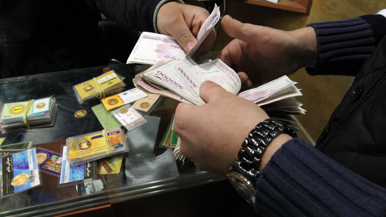 An Iranian trader exchanges a gold coin for cash in Tehran as sanctions make currency plummet in value.