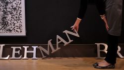   An employee poses for photographers with part of a Lehman Brothers company sign at Christie's auction house in London on September 24, 2010.  