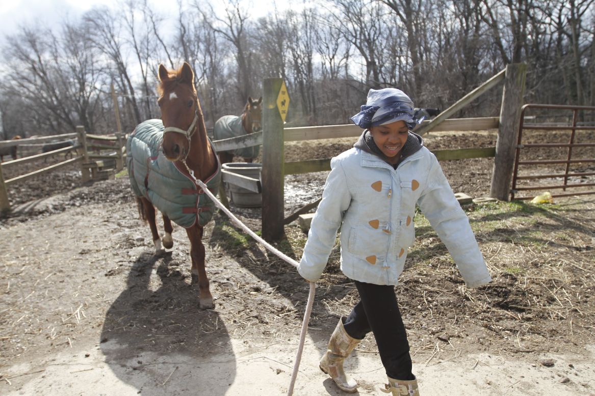 Sydney Rutledge walks a horse barn to the stables before going out to ride. Rutledge, 15, once afraid of horses, now plays on the Work To Ride women's polo team. Last year, while Hiner was dropping her off at home, she heard gunshots. "The worst thing I ever saw was (that) man get shot in front of me," she said.  "That's why I don't like being around where I live." 