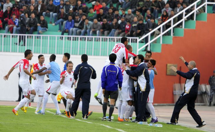 The Palestinian team celebrate their first goal against Nepal with members of the coaching staff on the touchline. Palestine won the match 2-0.