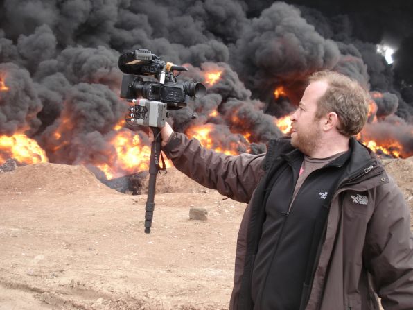 CNN senior photojournalist Neil Hallsworth films an oil fire in Homs, Syria.