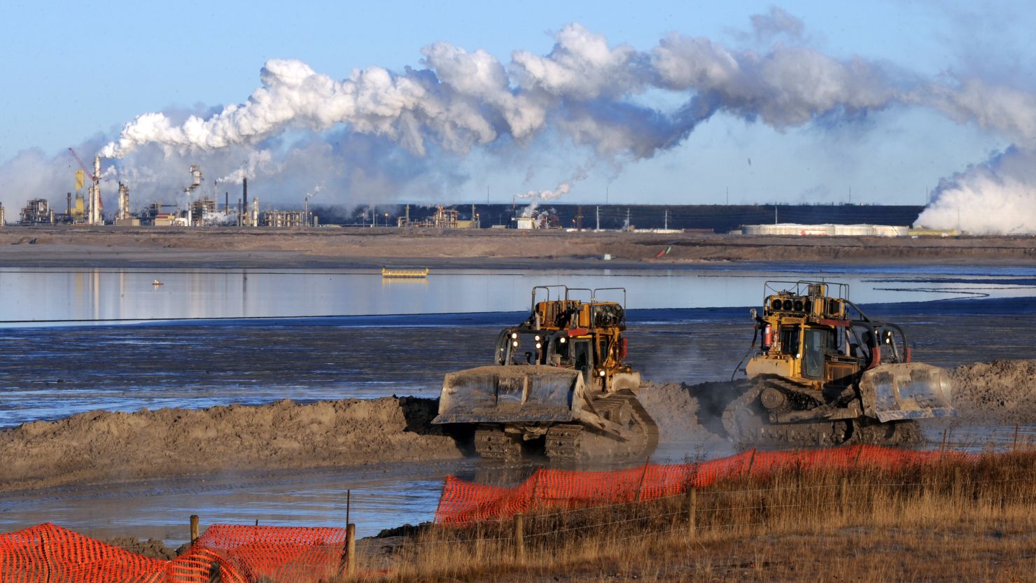 Workers use heavy machinery in the tailings pond at an oil sands extraction facility near Fort McMurray, Canada. 