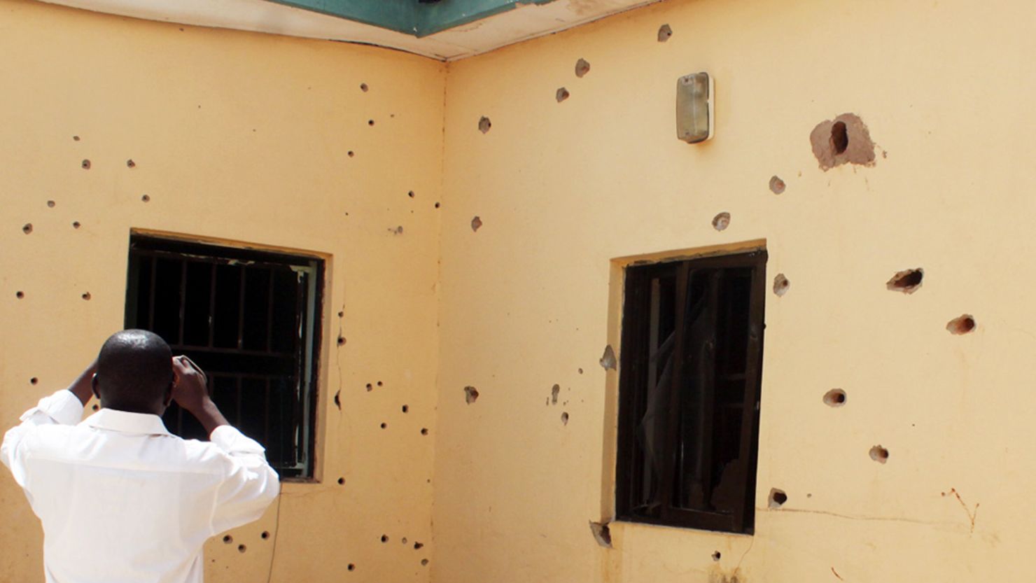 A man takes photos Friday of a bullet-riddled wall at the scene of the failed rescue operation in Nigeria.