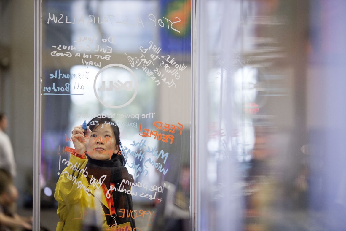 An attendee scrawls a message on a transparent board.