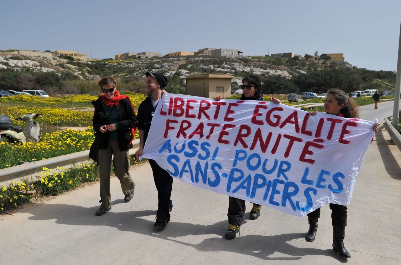 Demonstrators against Le Pen's visit hold a banner reading "Liberty, equality, fraternity, also for the illegal immigrants" in French.