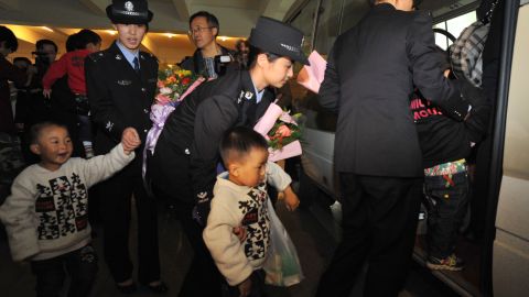 Policewomen lead a group of abducted children recently rescued from child traffickers, as they arrived back home to Guiyang on on October 19, 2011.