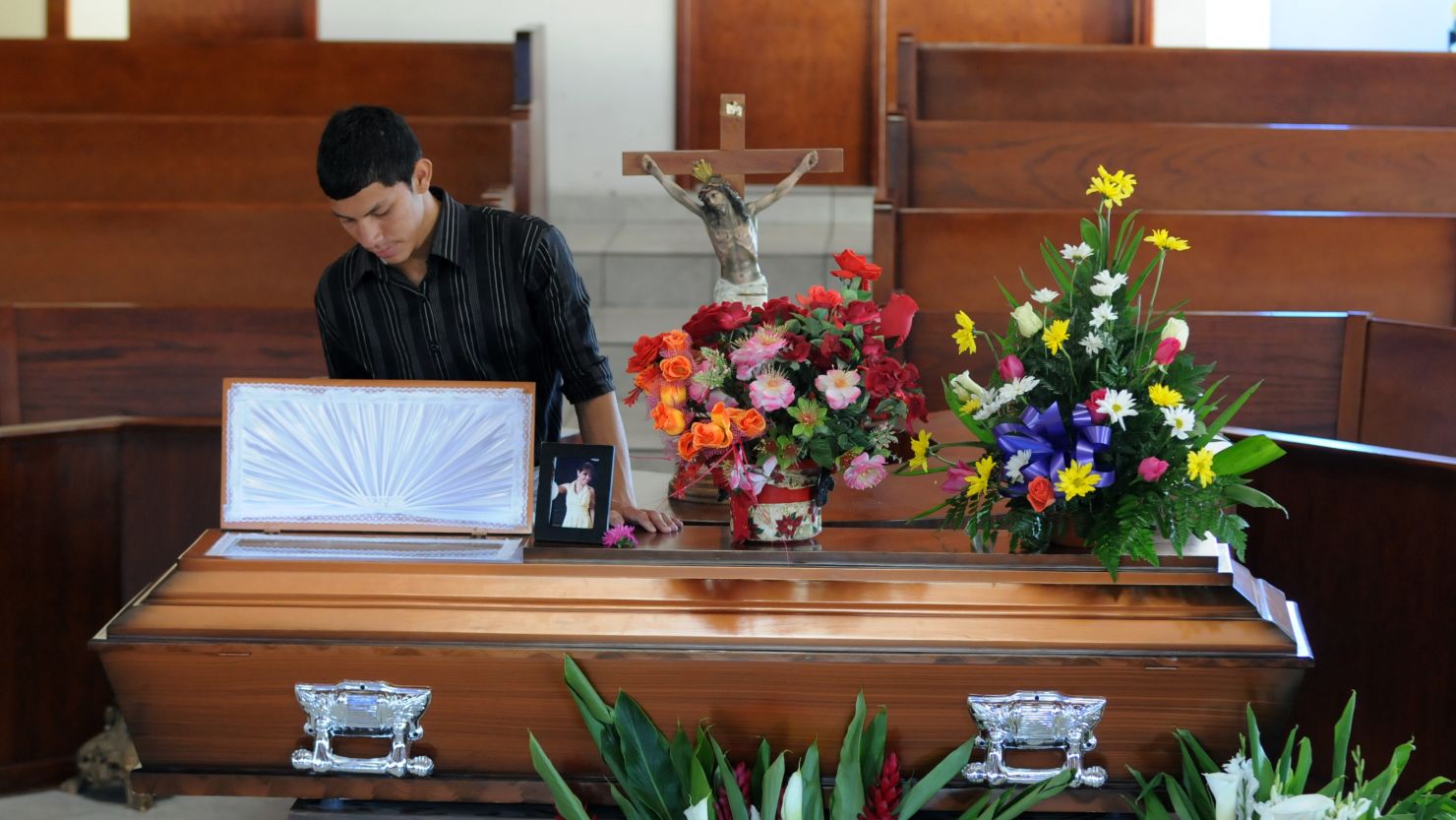 A young man stands beside the coffin of Honduran journalist Saira Fabiola Almendarez, murdered on March 2, 2012.