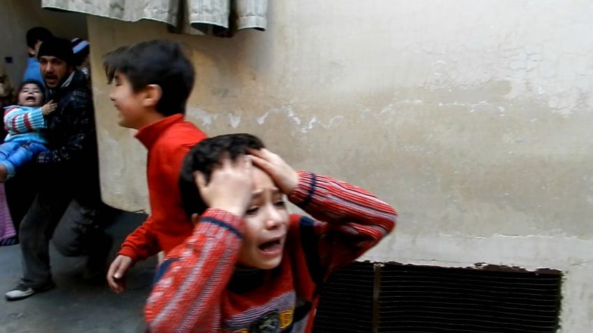 A man (L) runs carrying a toddler as children weep during fighting in Homs, on February 25, 2012.