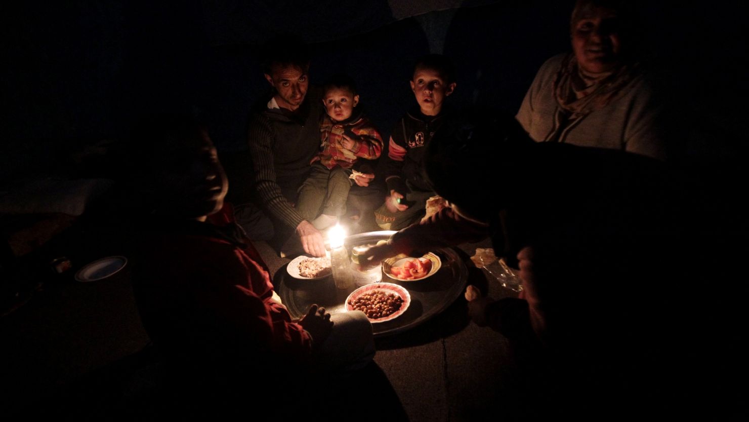 A Syrian family who fled the violence in Homs' Baba Amr neighborhood eats dinner during a blackout at a refugee center.