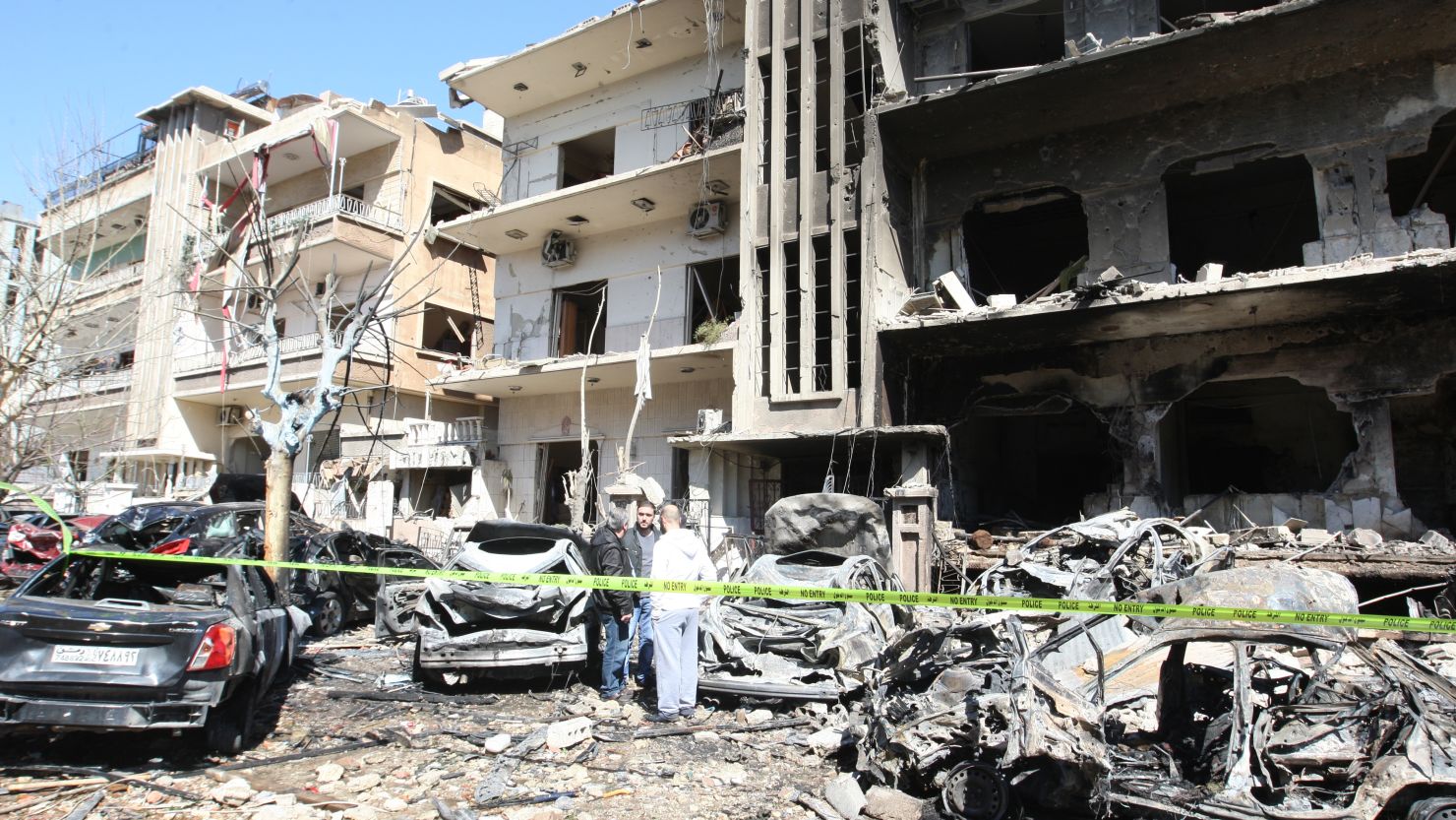 Syrian security officers inspects the scene at a destroyed building following twin bomb attacks in Damascus on Saturday.