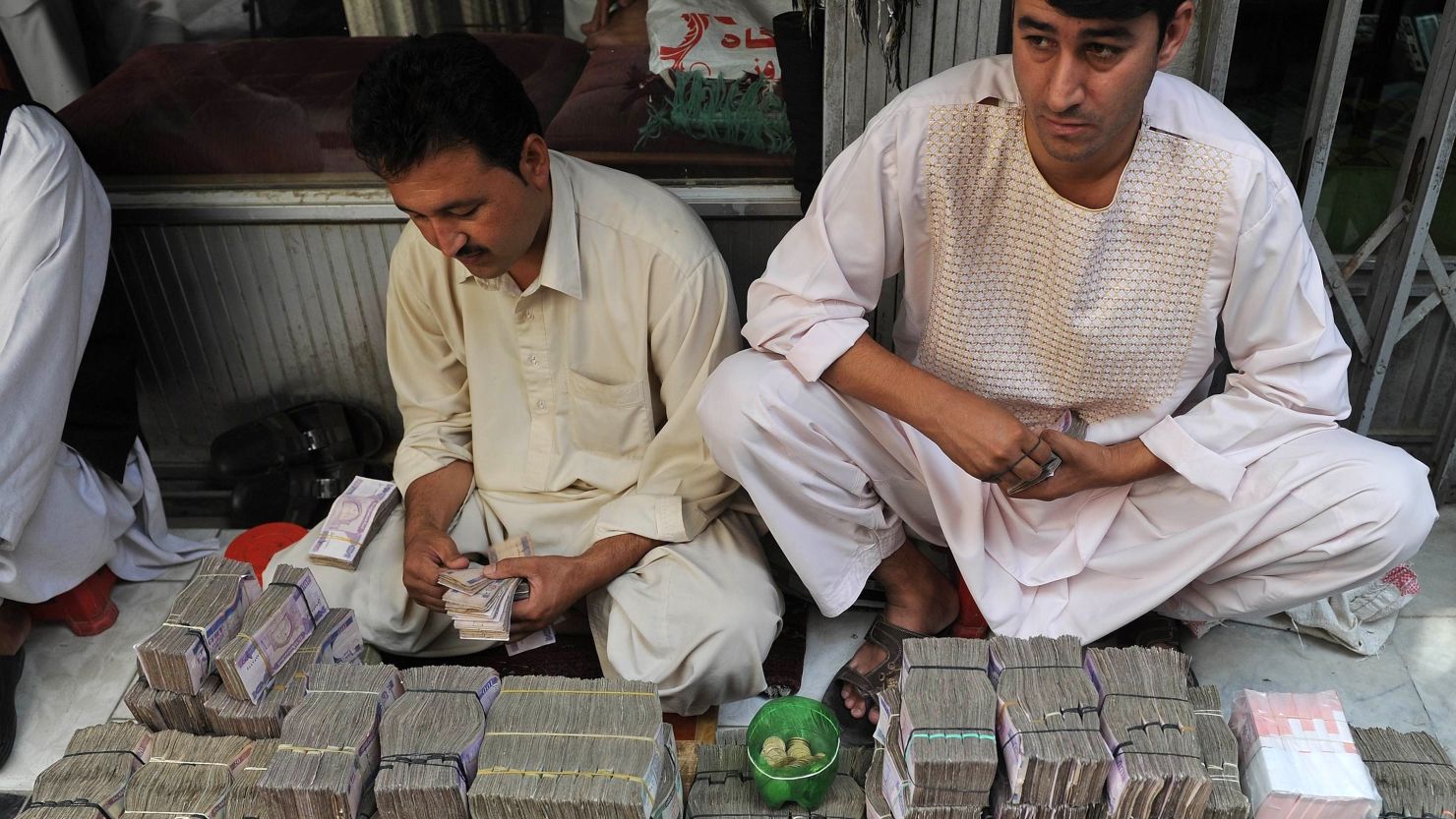 Afghani money changers count afghani bank notes at the exchange market in downtown Kabul on August 10, 2011