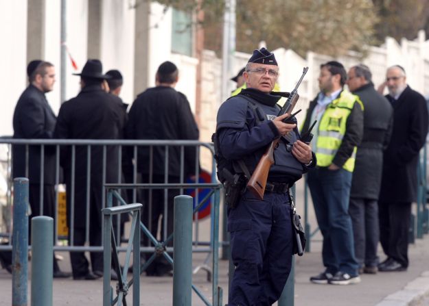 A policeman stands guard on Tuesday in front of the Jewish school where four people were killed the day before in Toulouse.