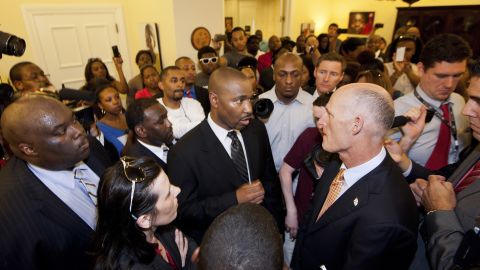Tallahassee defense attorney Deveron Brown talks to Florida Gov. Rick Scott, right, about the shooting of Trayvon Martin.