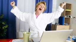 Woman in bathrobe yawning and stretching
