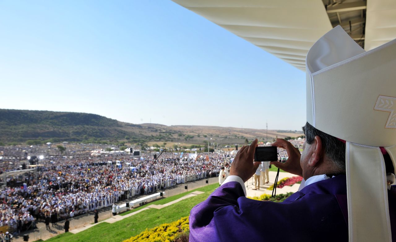 A bishop takes pictures during the Mass on Sunday. Cheering onlookers waved balloons, flags and banners as the pope arrived at Bicentennial Park in Mexico's Guanajuato state.
