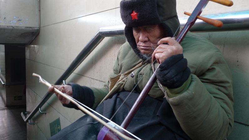 A blind man plays the erhu, a traditional Chinese instrument, in the entrance of a Beijing subway station. 