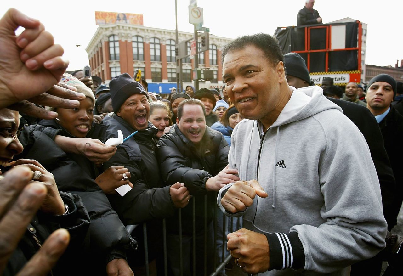 Boxing legend Muhammad Ali greets the crowd in a hoodie before unveiling a new wallscape for Adidas in Harlem.