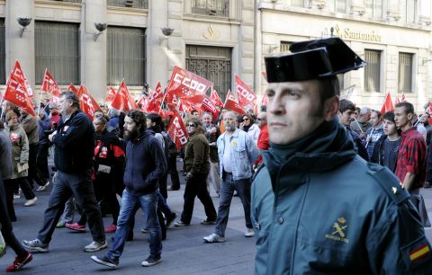 A "Guardia Civil" police officer walks along desmonstrators during a day of national strike in central Madrid.